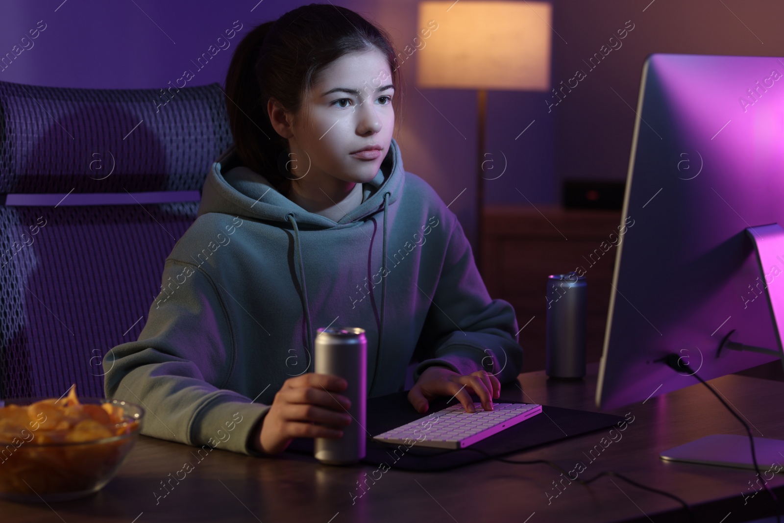 Photo of Girl with energy drink playing computer game at table in room