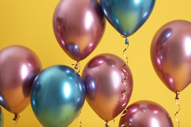 Bright balloons with ribbons on color background