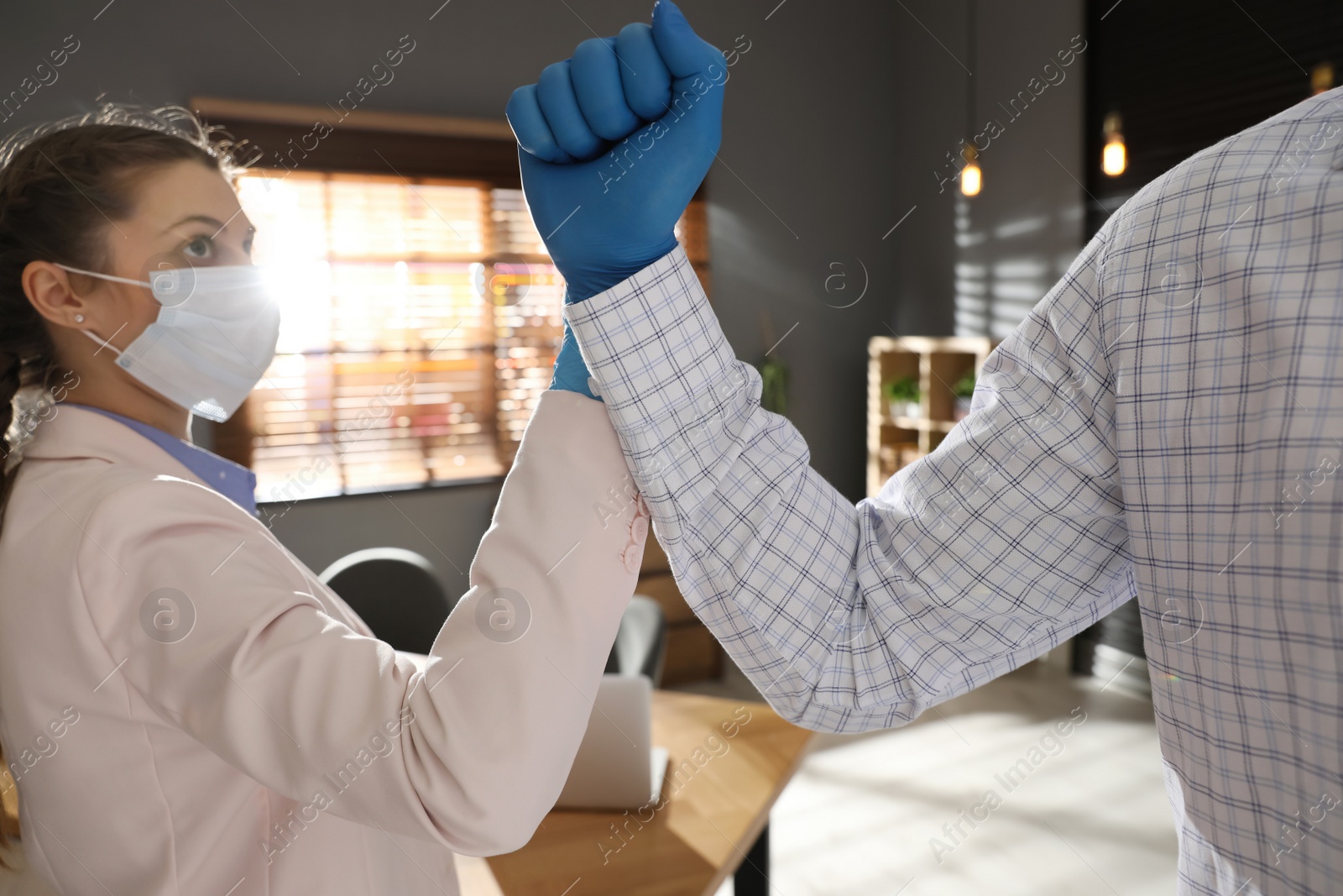 Photo of People greeting each other by bumping fists instead of handshake in office, closeup