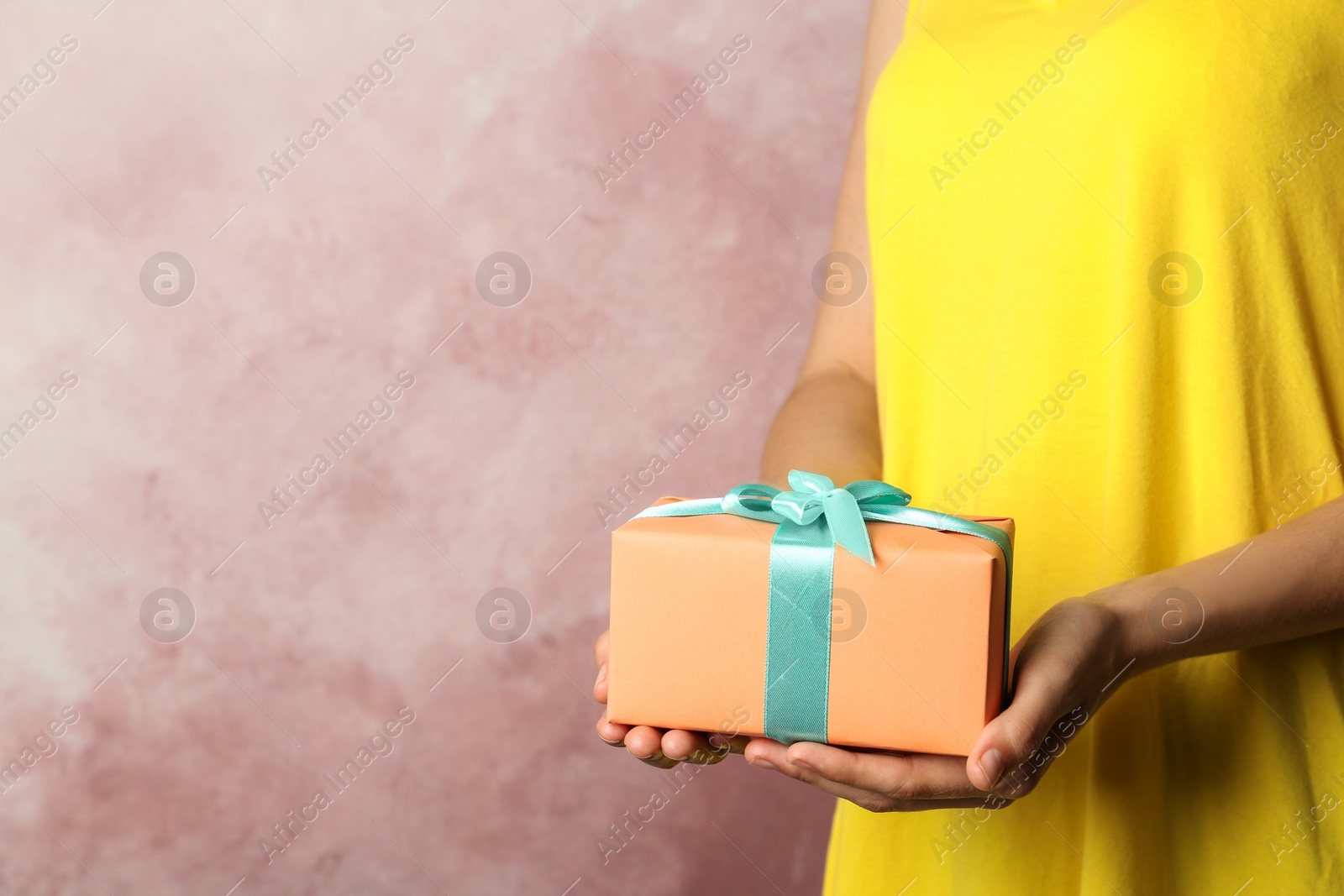 Photo of Woman holding beautifully wrapped gift box on color background