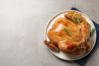 Tasty roasted chicken with rosemary and lemon on light grey table, top view. Space for text