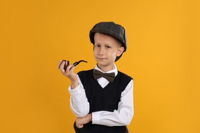 Photo of Cute little detective with smoking pipe on yellow background