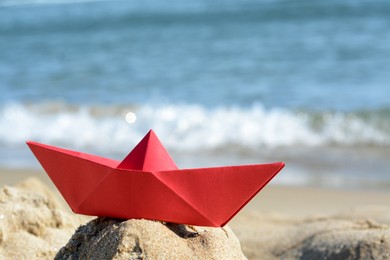 Photo of Red paper boat near sea on sunny day, closeup