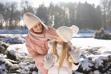 Family portrait of happy mother and her daughter in sunny snowy park