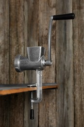 Photo of Metal manual meat grinder on table against wooden background