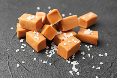 Photo of Delicious caramel candies with salt on dark background