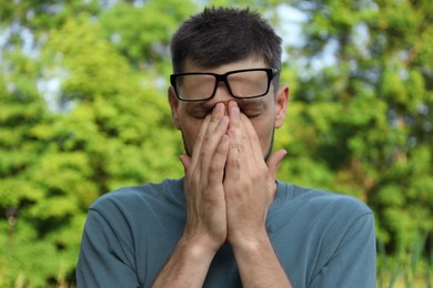 Man suffering from eyestrain outdoors on sunny day