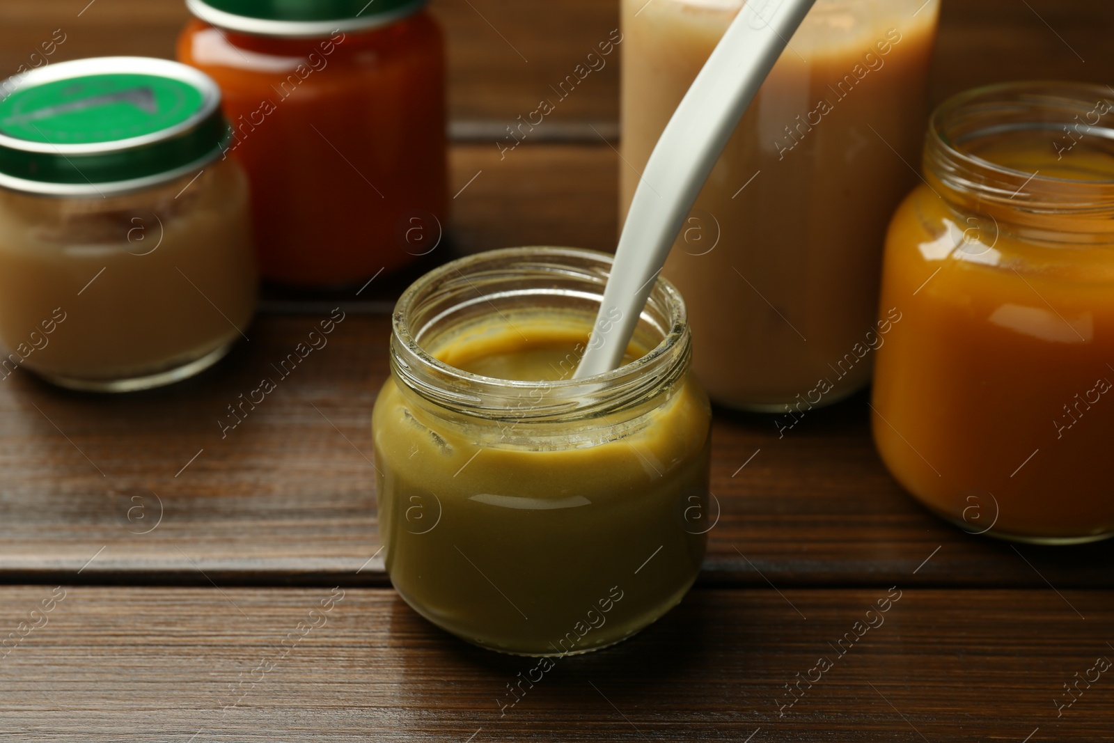 Photo of Tasty baby food in jars on wooden table