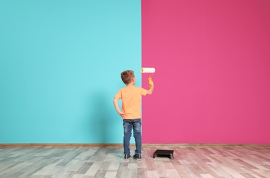 Photo of Little child painting color wall with roller brush