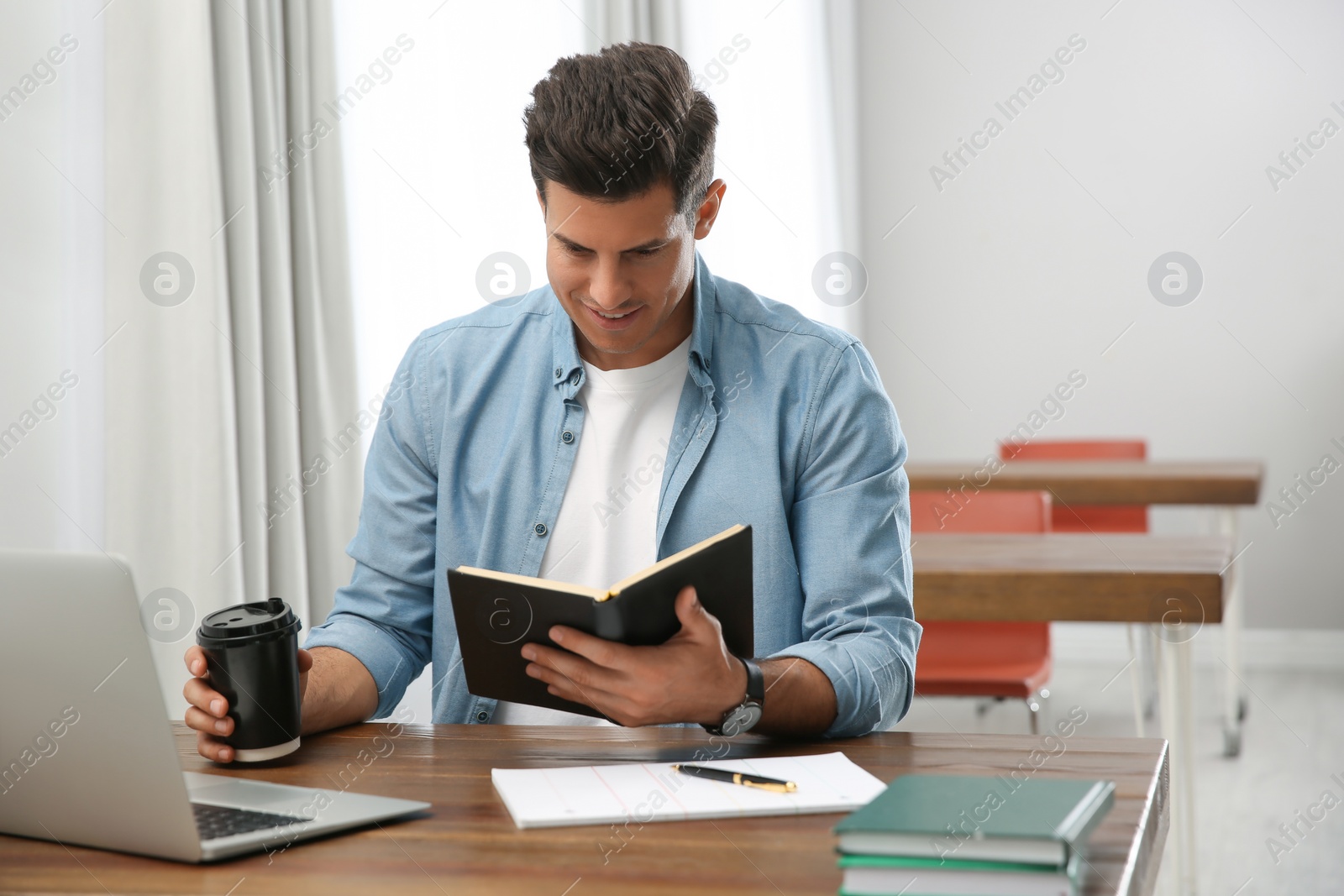 Photo of Man reading book at table in library