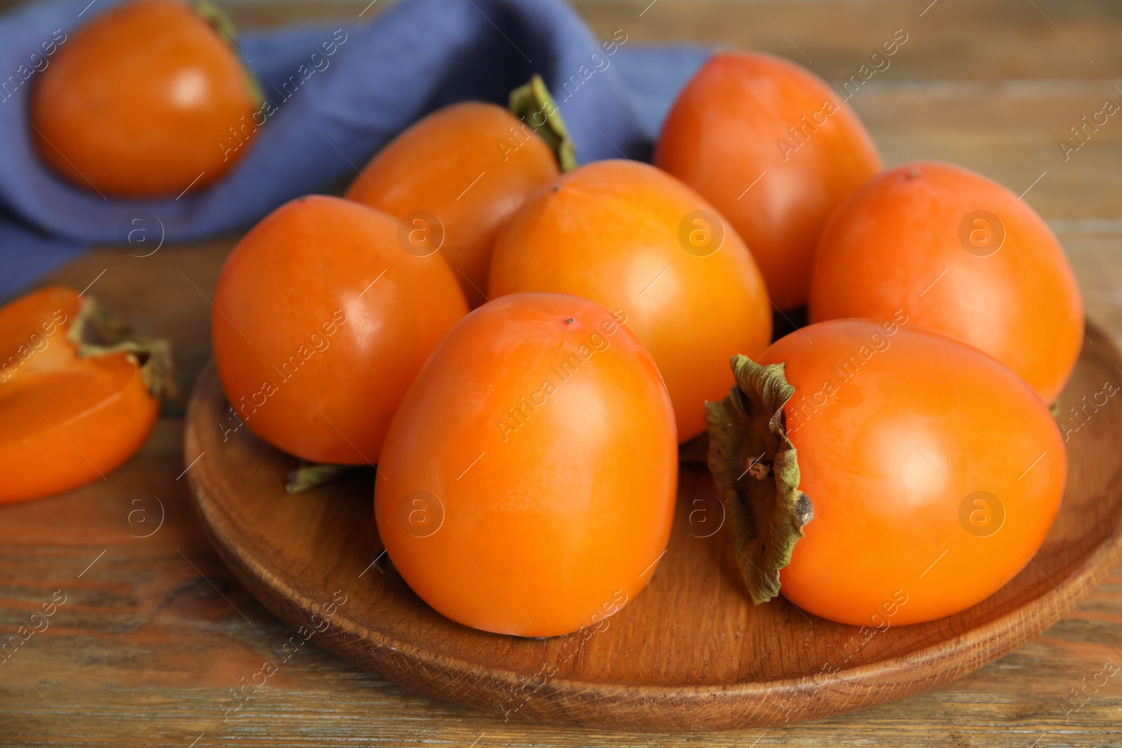 Photo of Tasty ripe persimmons on wooden table, closeup