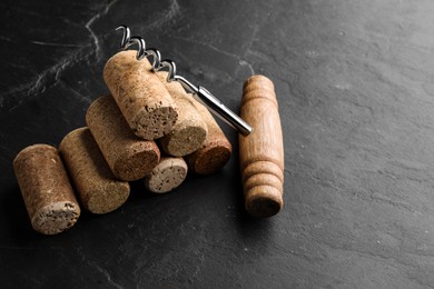 Photo of Corkscrew and stack of wine bottle stoppers on slate table