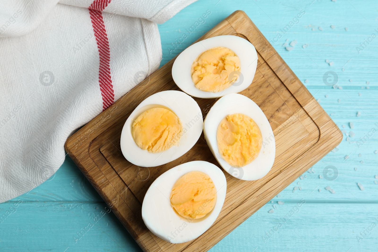Photo of Cut hard boiled chicken eggs on light blue wooden table, flat lay