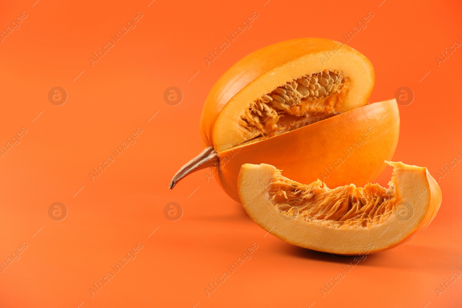 Photo of Cut fresh ripe pumpkin on orange background, space for text