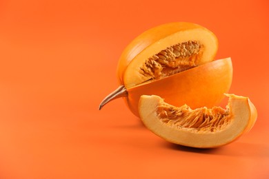 Photo of Cut fresh ripe pumpkin on orange background, space for text