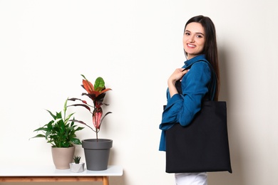 Photo of Beautiful young woman with stylish blank eco bag against color background