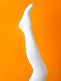 Leg mannequin in white tights on orange background