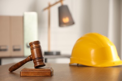 Photo of Law concept. Gavel and yellow hard hat on wooden table