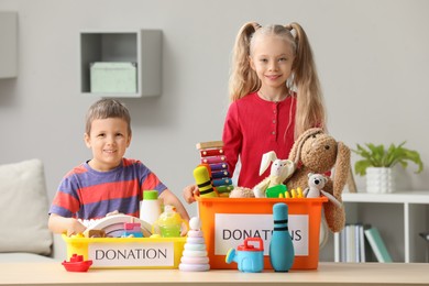 Photo of Cute little children sorting donation boxes at home