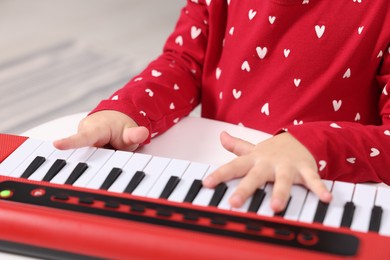 Photo of Little girl playing toy piano at home, closeup