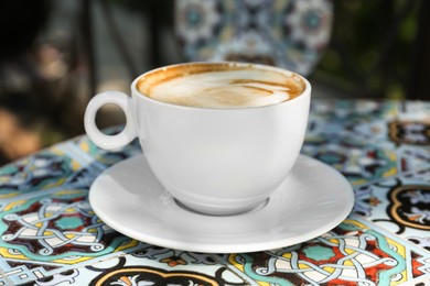 Photo of Cup of aromatic coffee on beautiful table in cafe outdoors