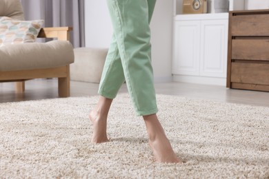 Woman walking on soft beige carpet at home, closeup