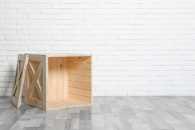 Photo of Wooden crate on floor at white brick wall. Space for text