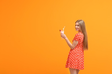 Photo of Young woman with glass of delicious milk shake on color background