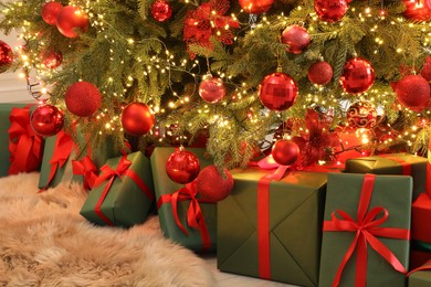 Photo of Many gift boxes under decorated Christmas tree indoors