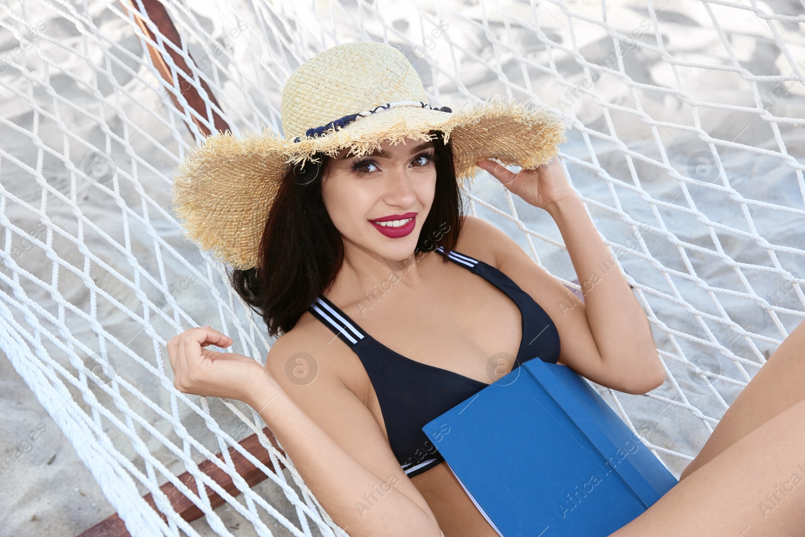 Photo of Young woman with book resting in hammock at seaside. Summer vacation