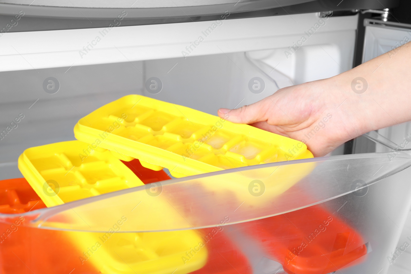 Photo of Woman taking tray with ice cubes from fridge, closeup