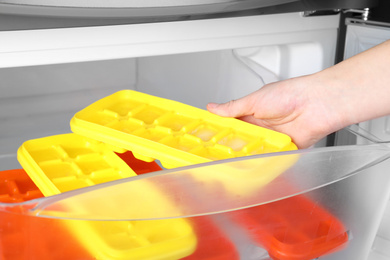 Photo of Woman taking tray with ice cubes from fridge, closeup