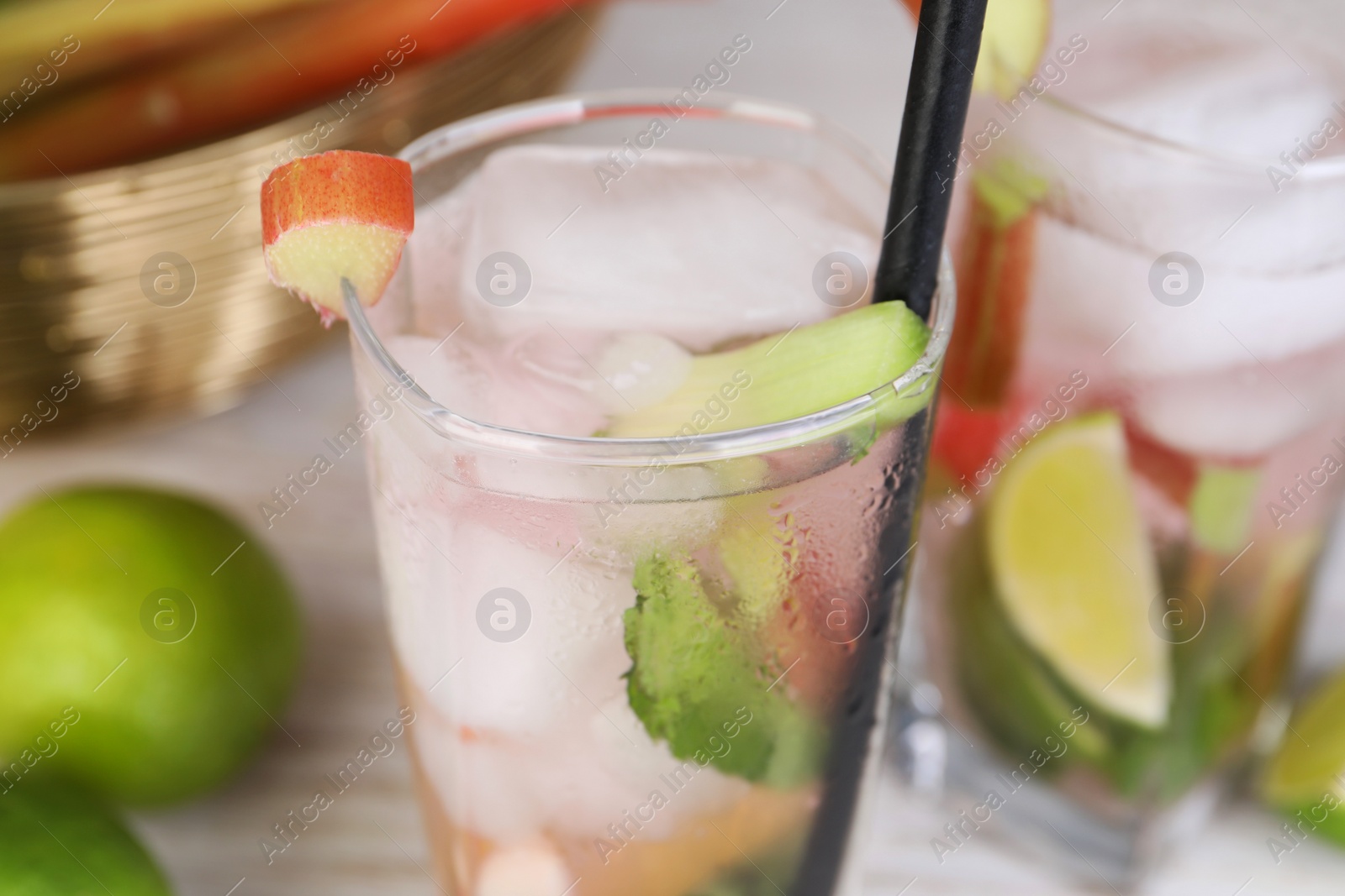 Photo of Glass of tasty rhubarb cocktail with lime on table, closeup