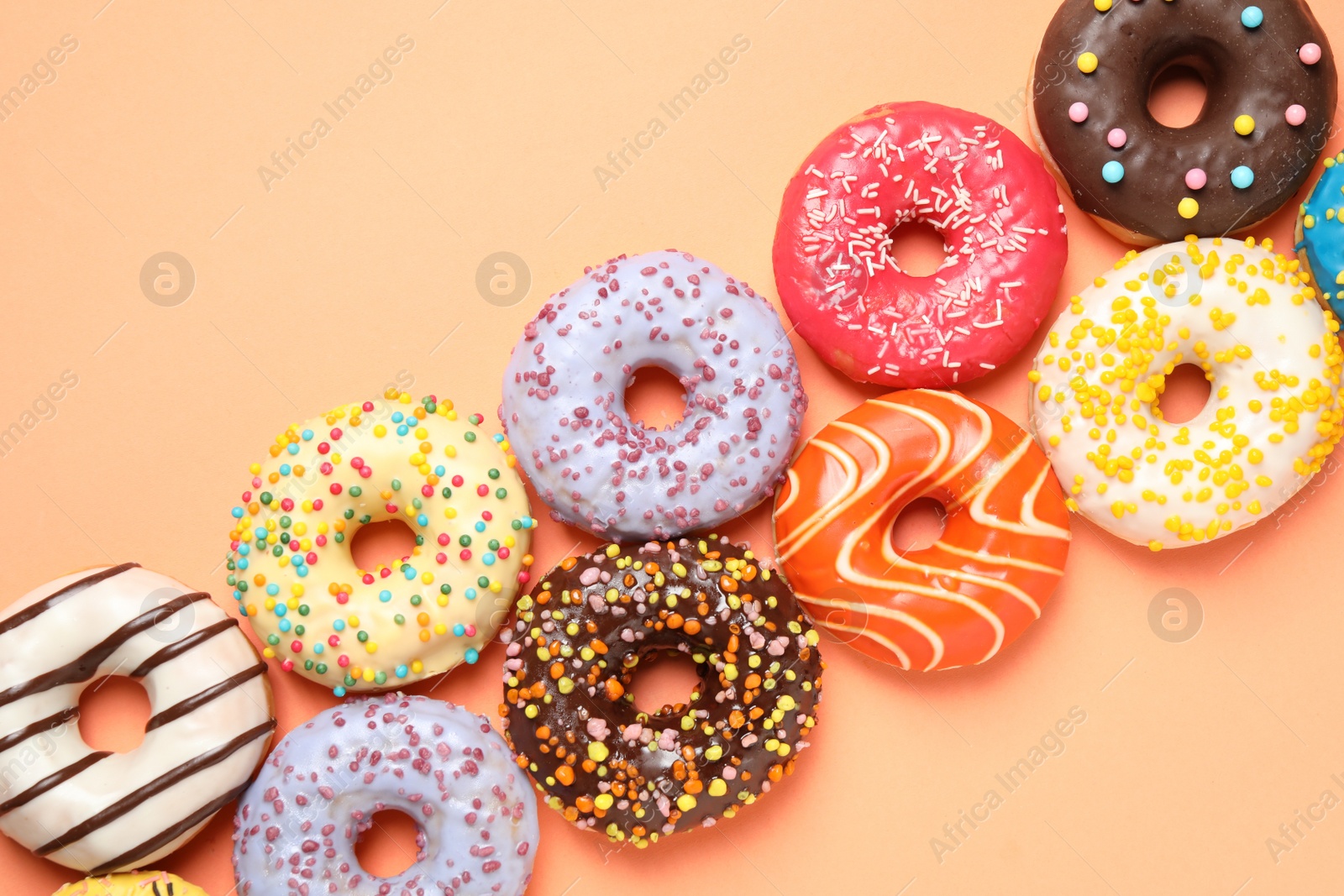 Photo of Delicious glazed donuts on orange background, flat lay