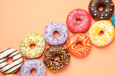 Photo of Delicious glazed donuts on orange background, flat lay