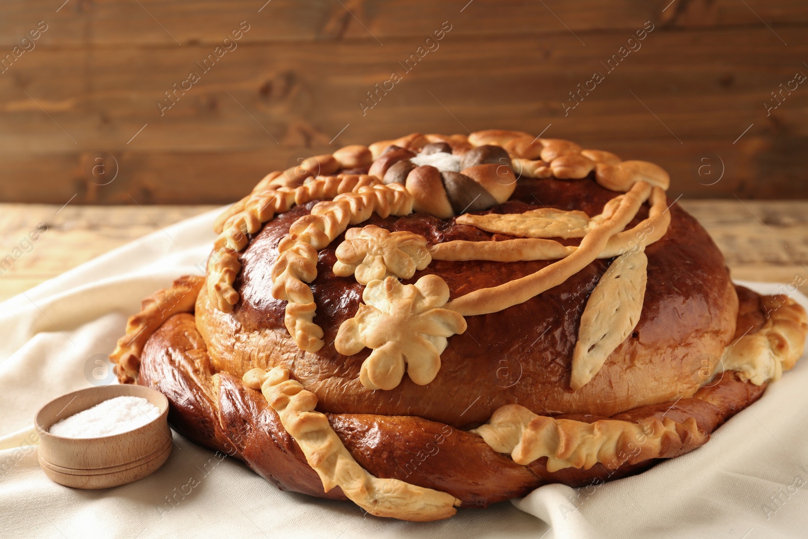 Photo of Korovai on tablecloth, closeup. Ukrainian bread and salt welcoming tradition