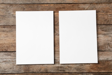 Photo of Blank paper sheets for brochure on wooden background, flat lay. Mock up