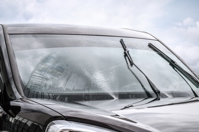 Photo of Washing car windscreen with wipers and liquid, closeup