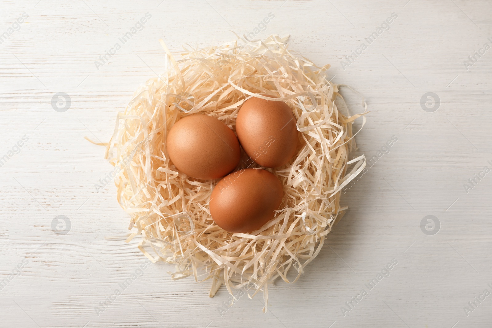 Photo of Nest with eggs on wooden background, top view. Pension concept