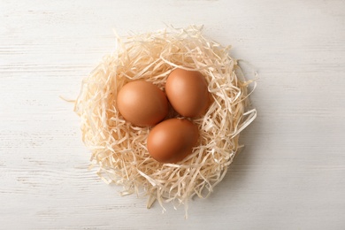 Photo of Nest with eggs on wooden background, top view. Pension concept