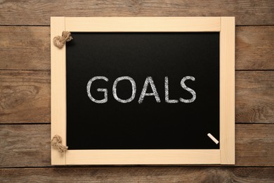 Image of Blackboard with word GOALS on wooden background, top view