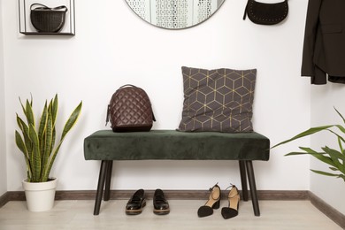 Photo of Stylish bench, shoes and backpack near light wall in hallway