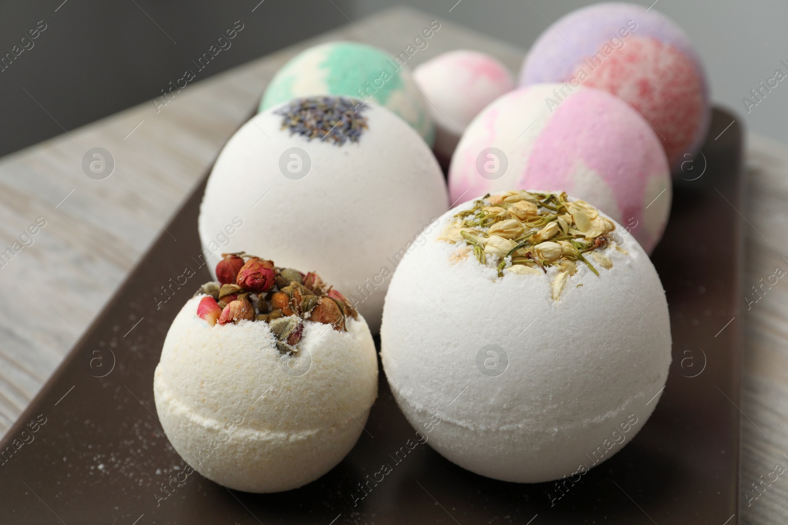 Photo of Plate with different bath bombs on wooden table, closeup