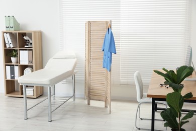 Modern medical office with doctor's workplace and examination table in clinic