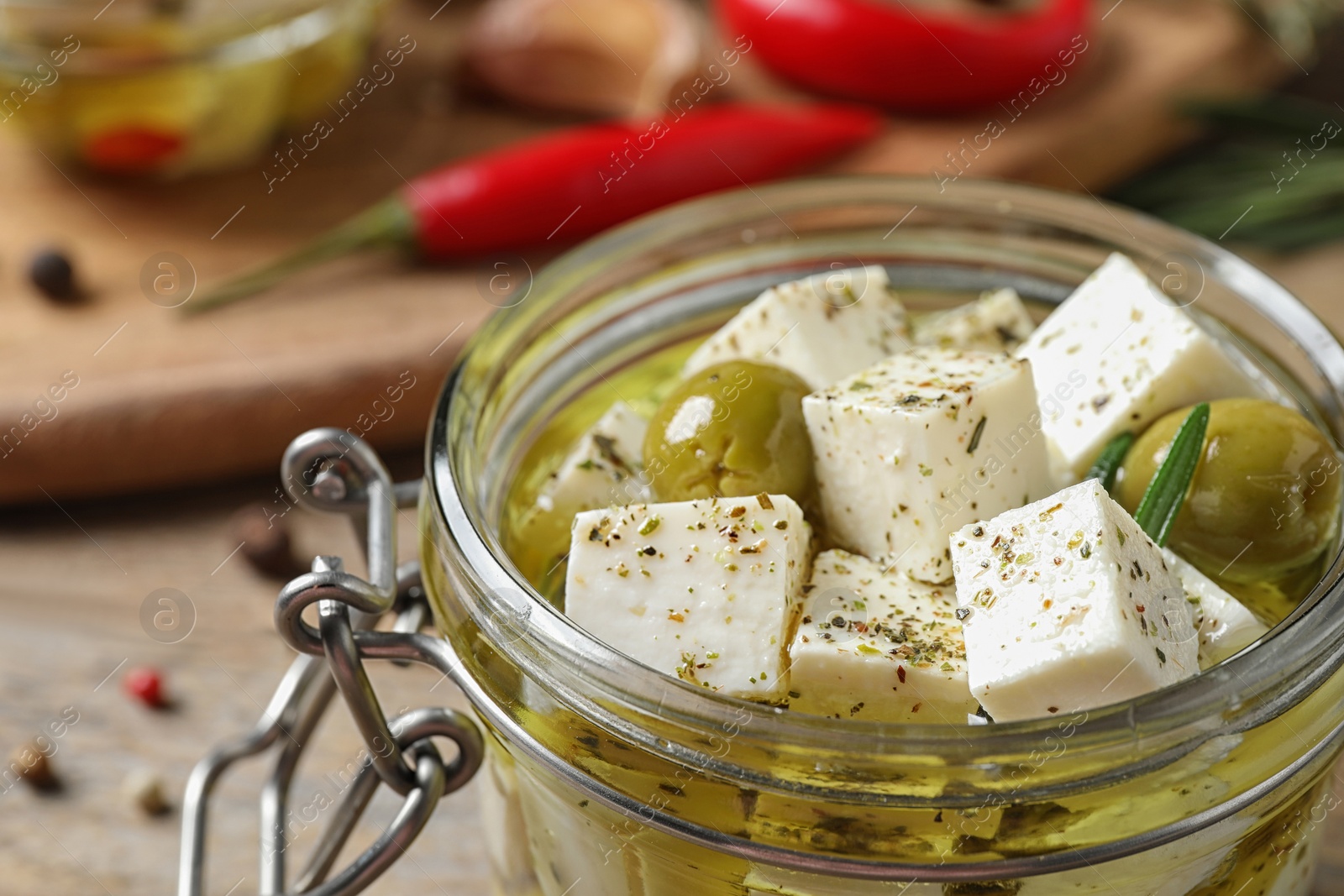 Photo of Pickled feta cheese in jar on wooden table, closeup