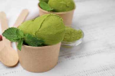 Paper cups with tasty matcha ice cream on white wooden table, closeup. Space for text