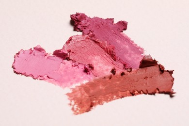 Photo of Smears of beautiful lipsticks on light background, closeup