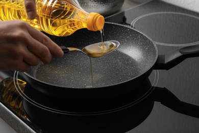 Woman pouring cooking oil from bottle into spoon, closeup