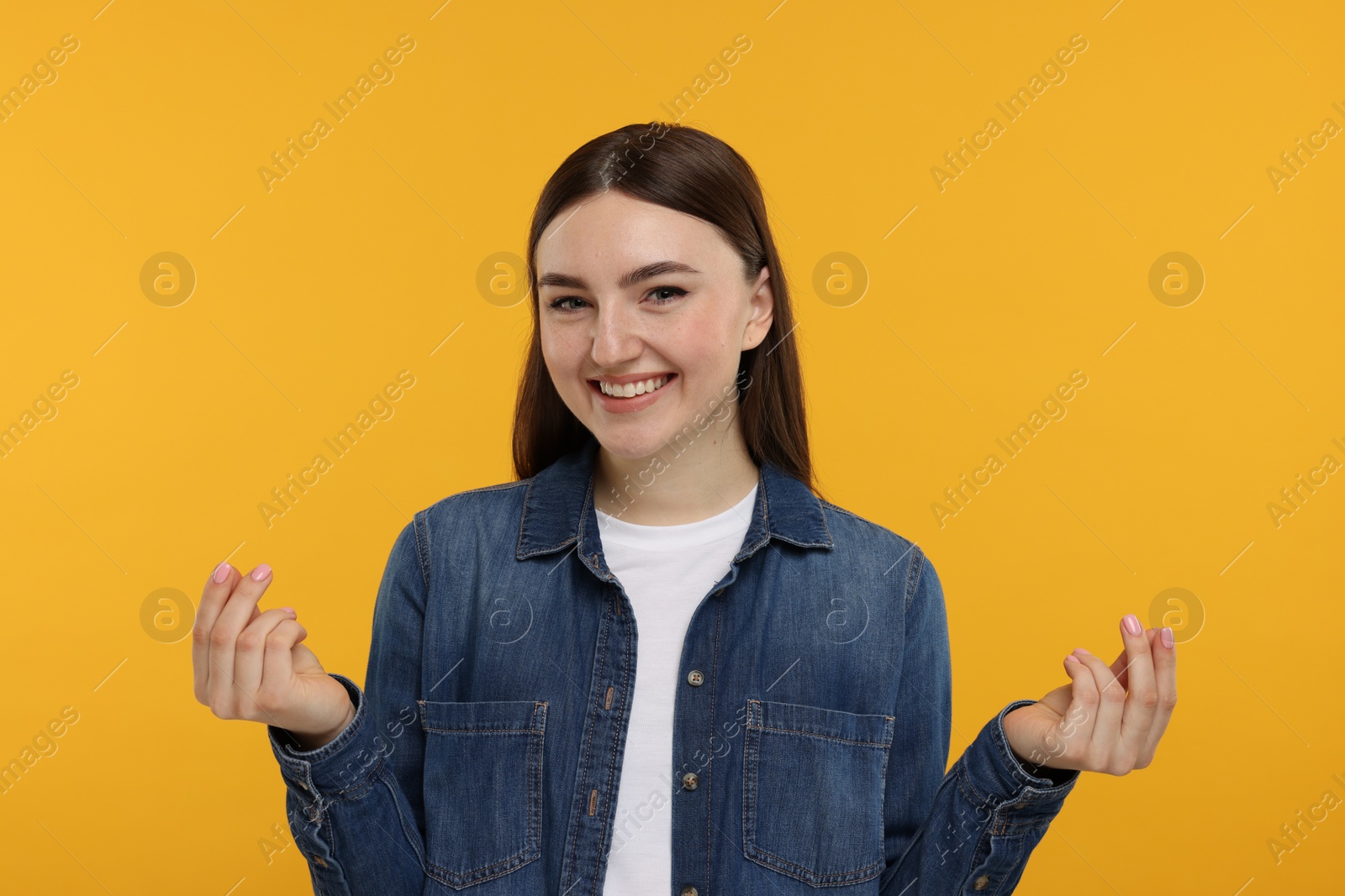 Photo of Happy woman showing money gesture on orange background