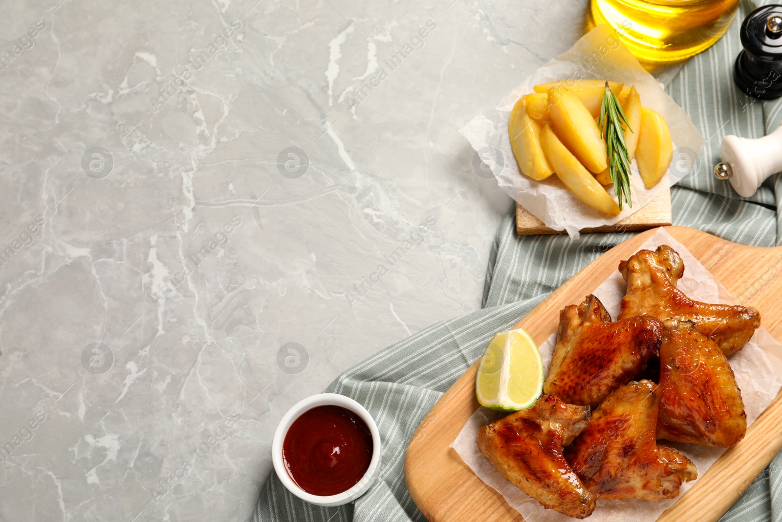 Photo of Delicious fried chicken wings on light gray marble table, flat lay. Space for text